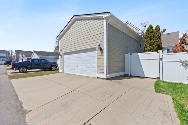 garage with a gate, driveway, and fence