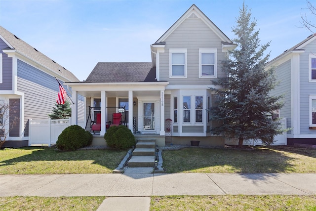 traditional home with roof with shingles, a porch, and a front lawn