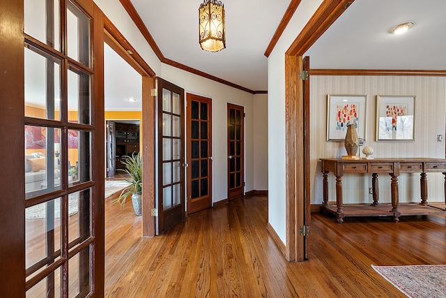 hall featuring baseboards, ornamental molding, french doors, and hardwood / wood-style floors