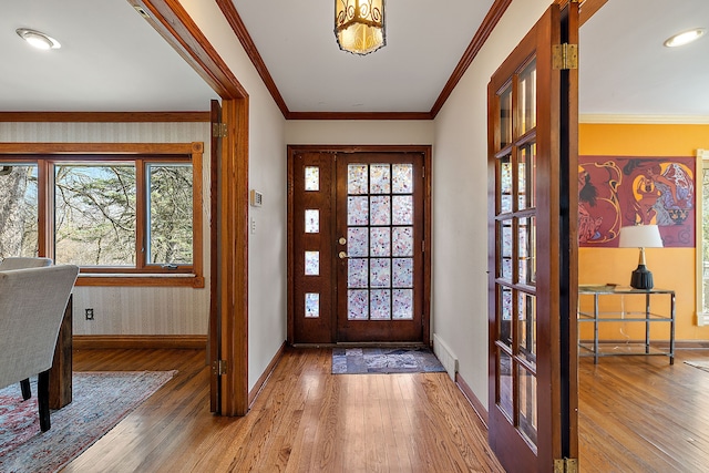 foyer featuring wood finished floors, visible vents, baseboards, and ornamental molding