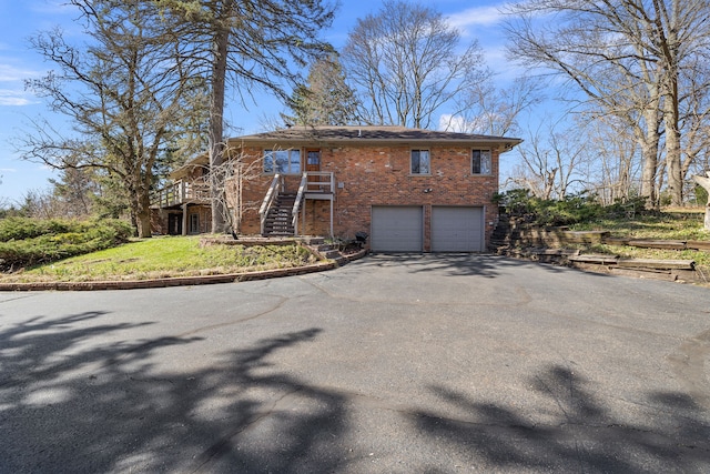 view of home's exterior with brick siding, an attached garage, stairway, and aphalt driveway