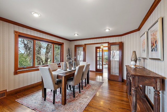 dining area featuring baseboards, ornamental molding, wood finished floors, and wallpapered walls