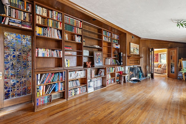 living area with wood finished floors, wood walls, and wall of books
