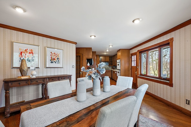 dining area with baseboards, crown molding, wood finished floors, and wallpapered walls