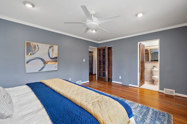 bedroom featuring wood finished floors, tile walls, baseboards, ornamental molding, and visible vents