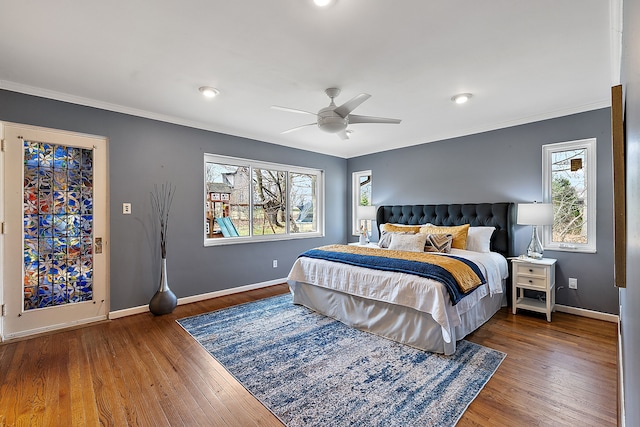bedroom with wood finished floors, crown molding, baseboards, and multiple windows