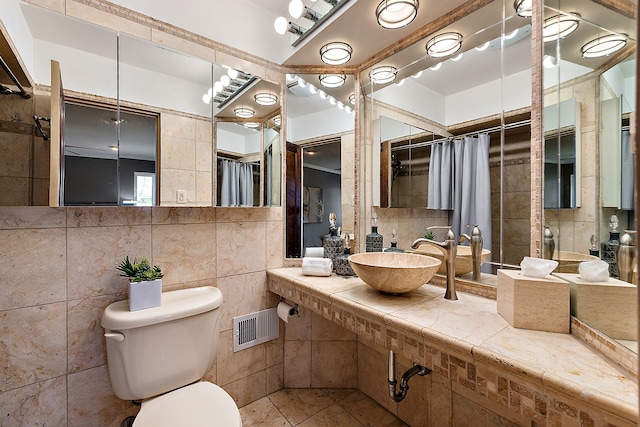 bathroom with a sink, tile walls, toilet, tile patterned flooring, and visible vents