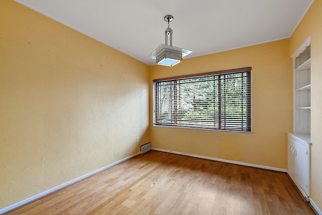 unfurnished dining area with wood finished floors, visible vents, and baseboards