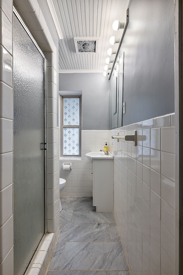 bathroom featuring tile walls, vanity, a shower stall, and toilet