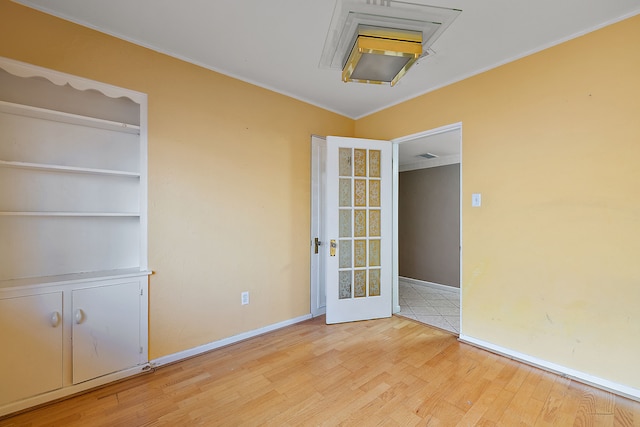 spare room with light wood finished floors, baseboards, ornamental molding, and visible vents