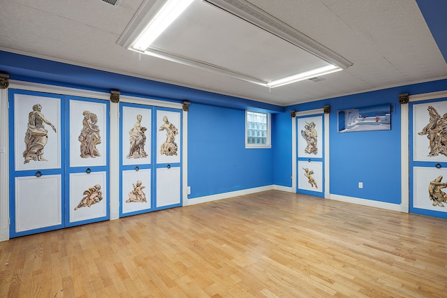 unfurnished room with attic access, baseboards, and wood finished floors