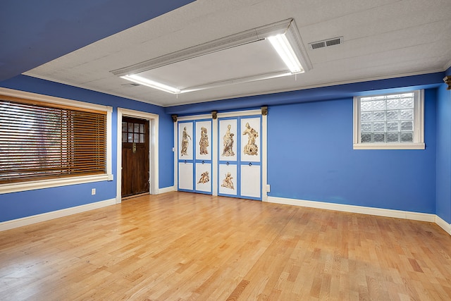 unfurnished room with attic access, wood finished floors, visible vents, and baseboards