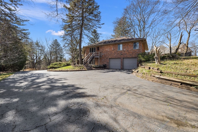 view of property exterior featuring aphalt driveway, brick siding, stairs, and a garage