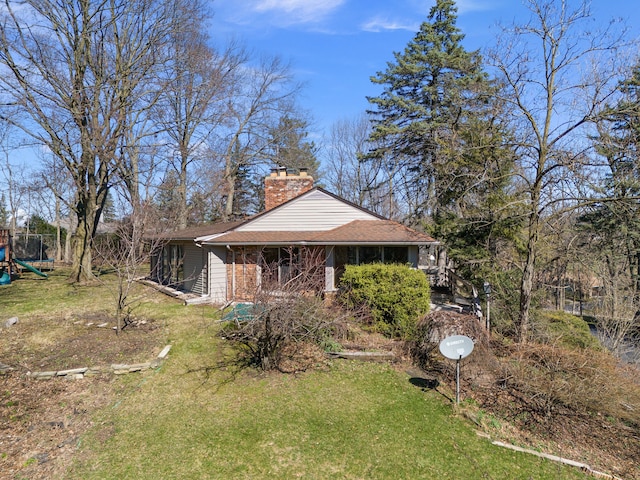 view of side of home featuring a lawn, a chimney, a playground, and a shingled roof