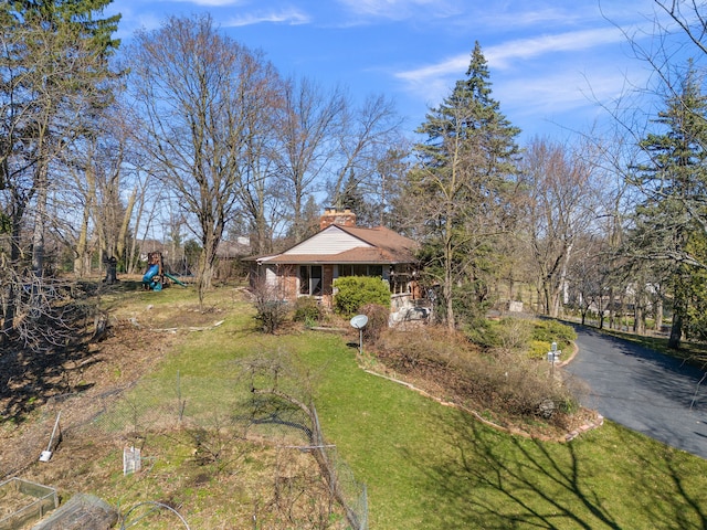 view of yard with aphalt driveway and a playground