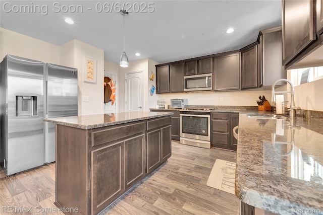 51306 Kirby Dr, Chesterfield, MI 48047 - kitchen with stainless steel appliances, a sink, dark brown cabinets, light stone counters, and light wood-type flooring