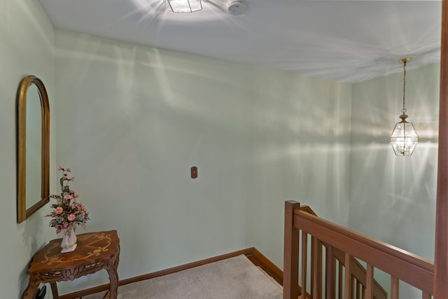 hallway featuring carpet floors, baseboards, and an upstairs landing