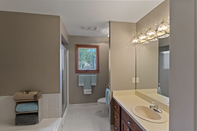 bathroom featuring tile patterned flooring, a shower with shower door, baseboards, vanity, and toilet