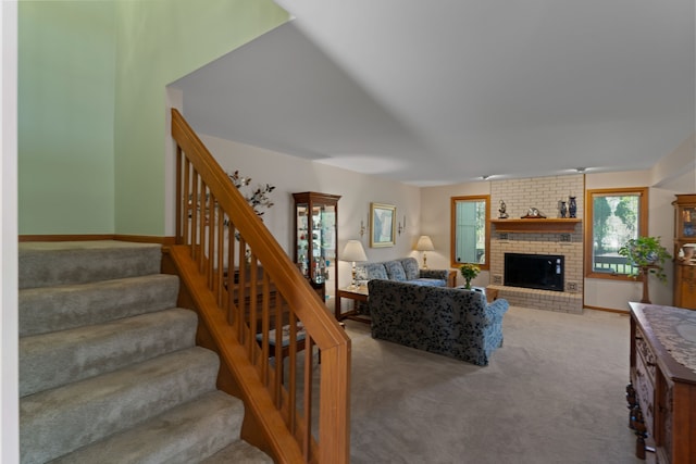 living area with a brick fireplace, stairs, and carpet