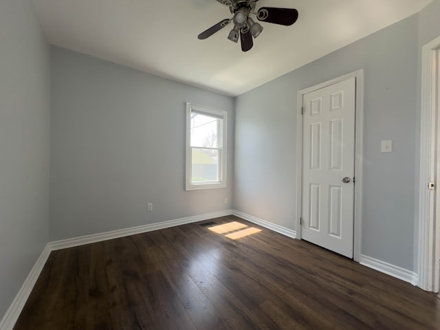 unfurnished bedroom with baseboards, dark wood finished floors, and a ceiling fan