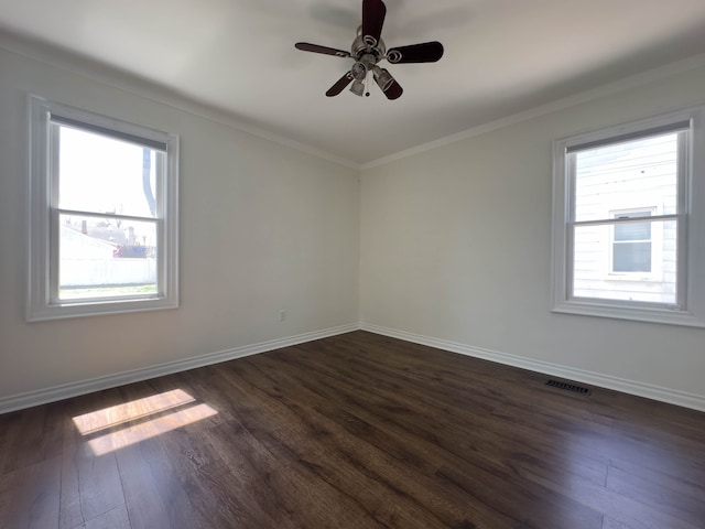 spare room featuring dark wood finished floors, plenty of natural light, baseboards, and crown molding