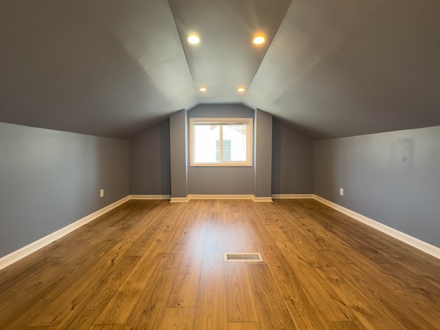 additional living space featuring lofted ceiling, wood finished floors, baseboards, and recessed lighting