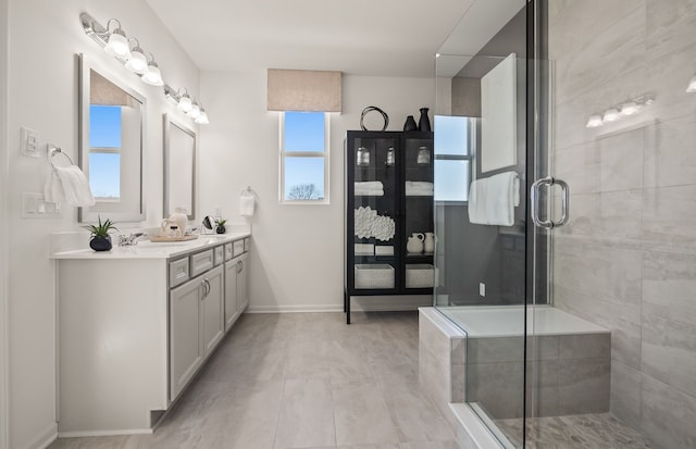 full bathroom with baseboards, a sink, double vanity, and a stall shower