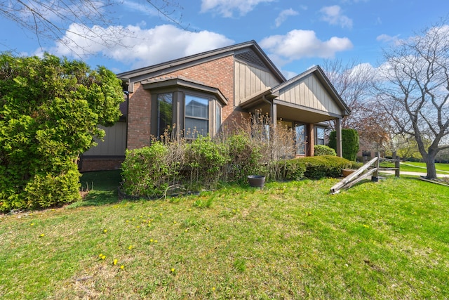 view of side of home with a lawn, brick siding, and board and batten siding