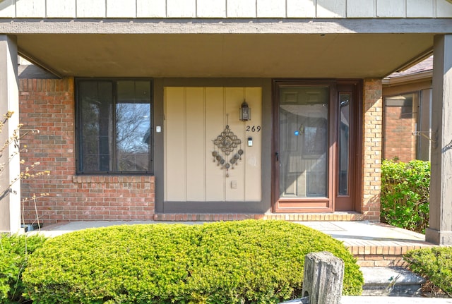 view of exterior entry featuring brick siding and board and batten siding