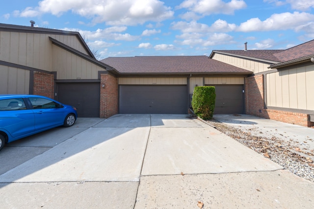 view of front of home featuring an attached garage, a shingled roof, brick siding, and concrete driveway