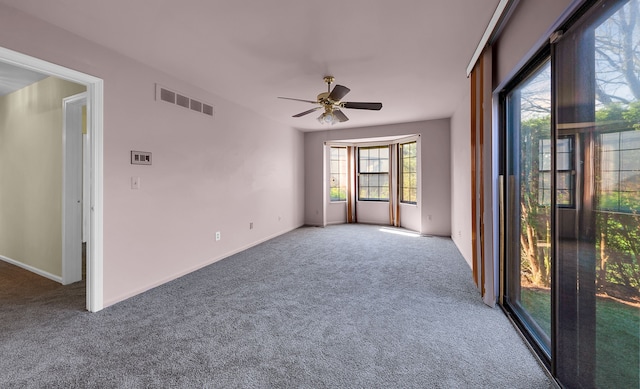 carpeted empty room with visible vents, a ceiling fan, and baseboards
