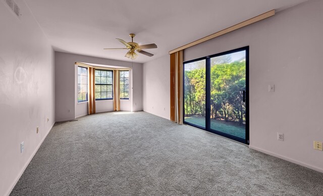 carpeted spare room with ceiling fan, baseboards, and visible vents