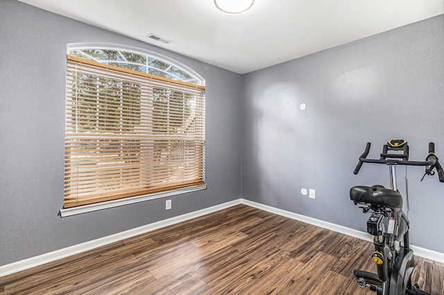 workout area featuring baseboards, visible vents, and wood finished floors