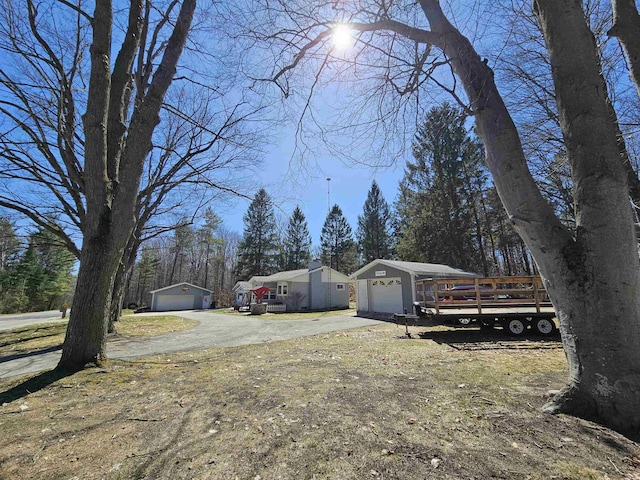 view of yard featuring an outdoor structure, aphalt driveway, and a garage