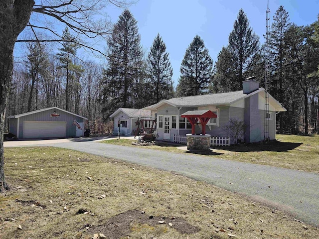 ranch-style house with a chimney, a garage, an outdoor structure, a front yard, and aphalt driveway