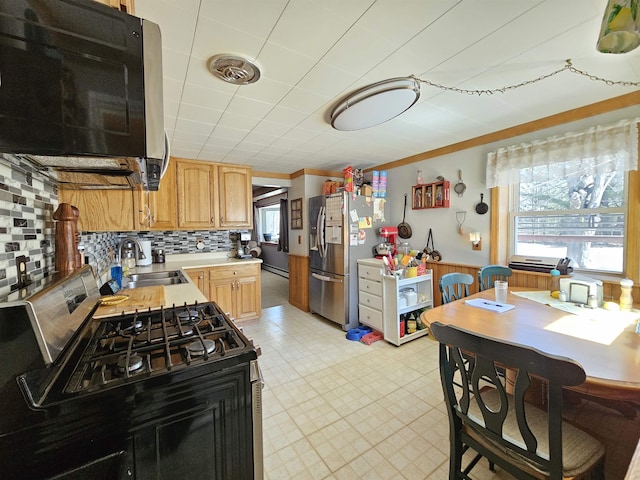 kitchen featuring light countertops, a healthy amount of sunlight, stainless steel refrigerator with ice dispenser, and a sink
