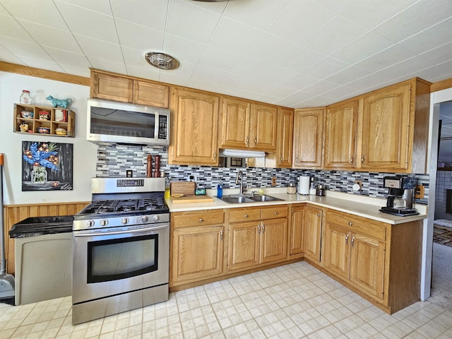 kitchen featuring light countertops, appliances with stainless steel finishes, decorative backsplash, and a sink