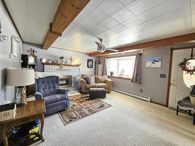 living room featuring a baseboard radiator, ceiling fan, beamed ceiling, a fireplace, and carpet flooring