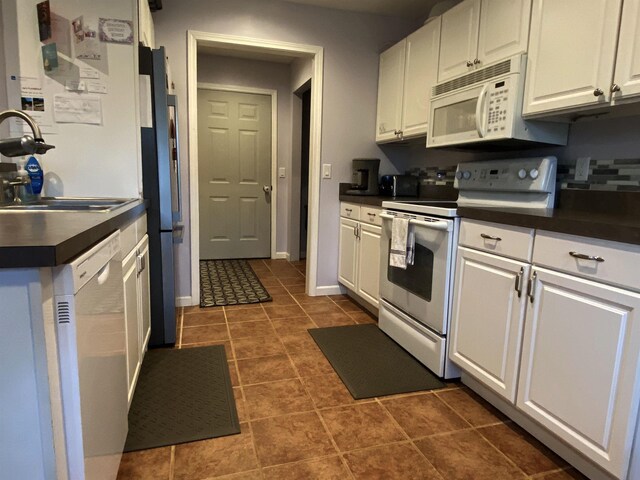 835 Eden St, Kingsley, MI 49649 - kitchen featuring dark countertops, a sink, white appliances, white cabinets, and dark tile patterned floors