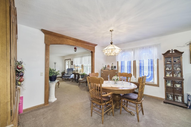 9155 Ivanhoe Dr, Onekama, MI 49675 - dining space featuring baseboards, a notable chandelier, and carpet flooring