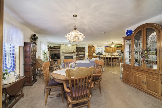 9155 Ivanhoe Dr, Onekama, MI 49675 - dining space featuring an inviting chandelier, a fireplace, and light colored carpet