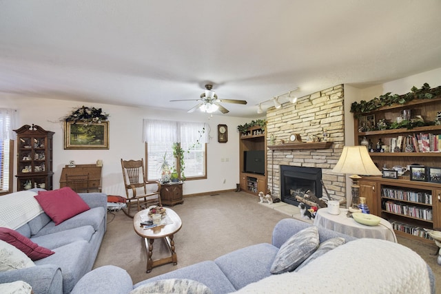 9155 Ivanhoe Dr, Onekama, MI 49675 - carpeted living area featuring a ceiling fan, baseboards, a fireplace, and rail lighting