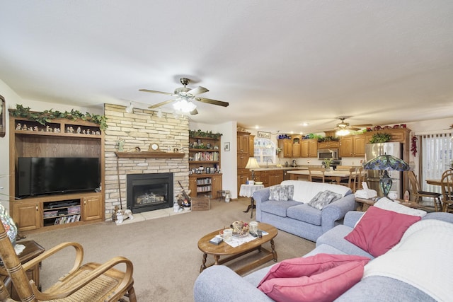 9155 Ivanhoe Dr, Onekama, MI 49675 - carpeted living area featuring a stone fireplace, a ceiling fan, and a sink