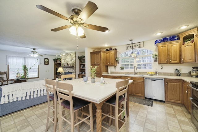 9155 Ivanhoe Dr, Onekama, MI 49675 - kitchen with light countertops, a ceiling fan, a sink, a fireplace, and appliances with stainless steel finishes