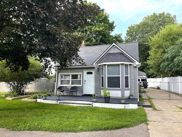 view of front of property with fence, a front lawn, roof with shingles, and a deck