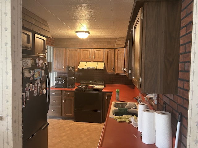 kitchen featuring light floors, under cabinet range hood, a sink, and black appliances