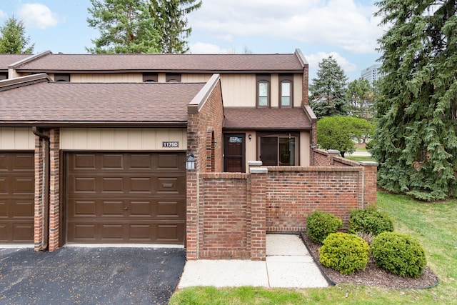 view of front of property featuring brick siding, roof with shingles, and aphalt driveway