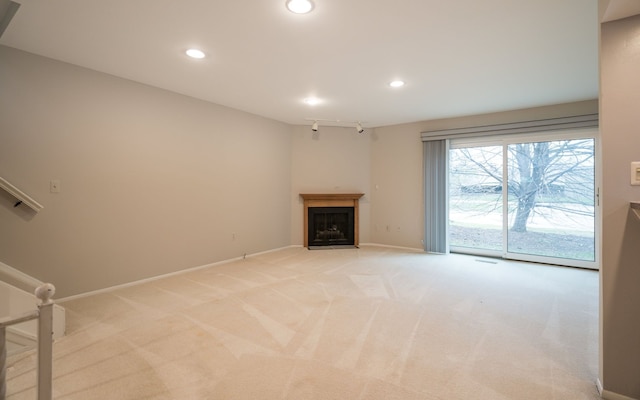 unfurnished living room featuring a fireplace with flush hearth, light carpet, baseboards, and recessed lighting
