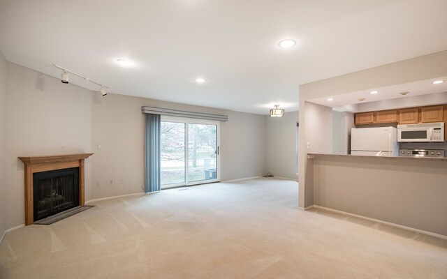unfurnished living room with recessed lighting, a fireplace with flush hearth, baseboards, and light colored carpet