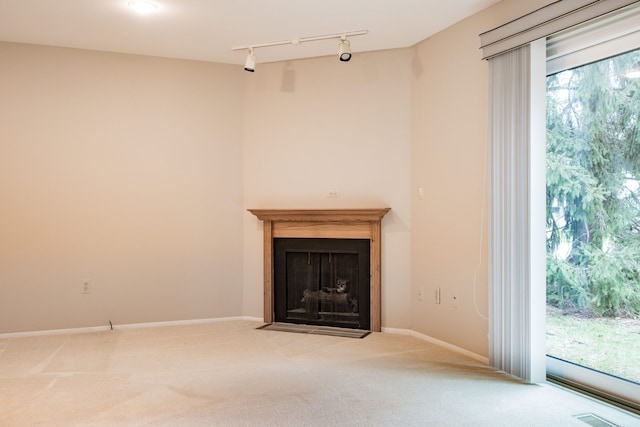 unfurnished living room featuring a fireplace with flush hearth, baseboards, visible vents, track lighting, and carpet floors